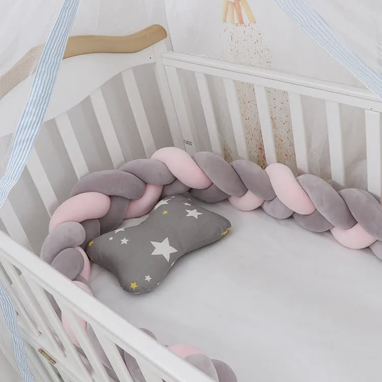 Braided knot design crib bumper in spandex velvet, shown in a light grey colour wrapped around crib slats.