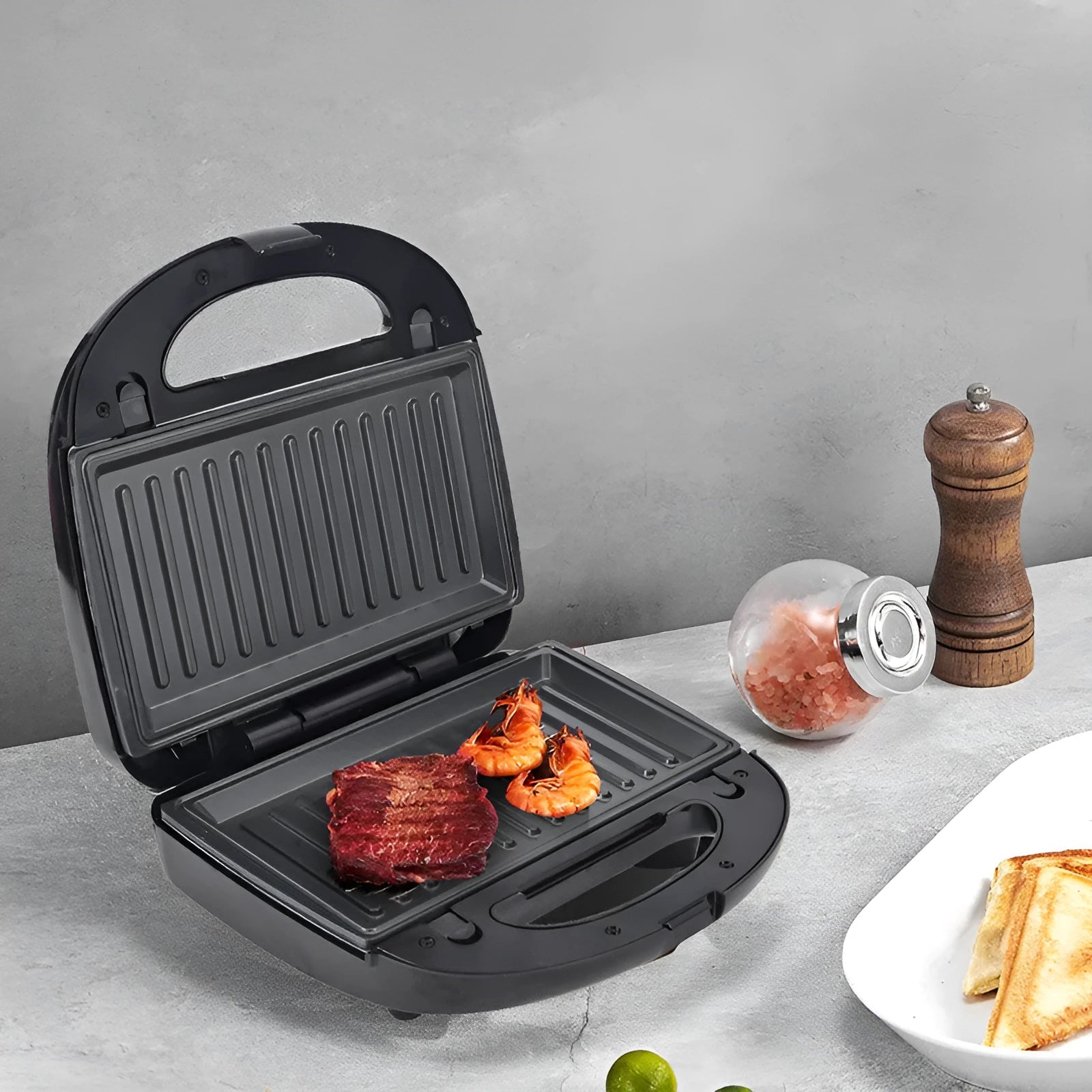 Black double-sided electric sandwich pan with stainless steel lid and six non-stick pans.