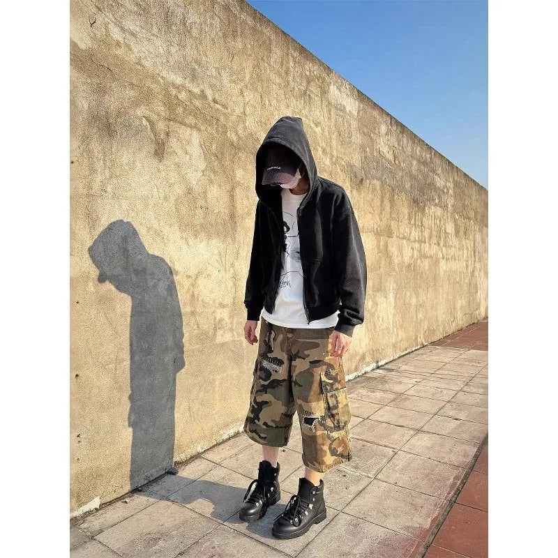 Man wearing loose fit camouflage print cropped jeans with ripped knees and patchwork details.