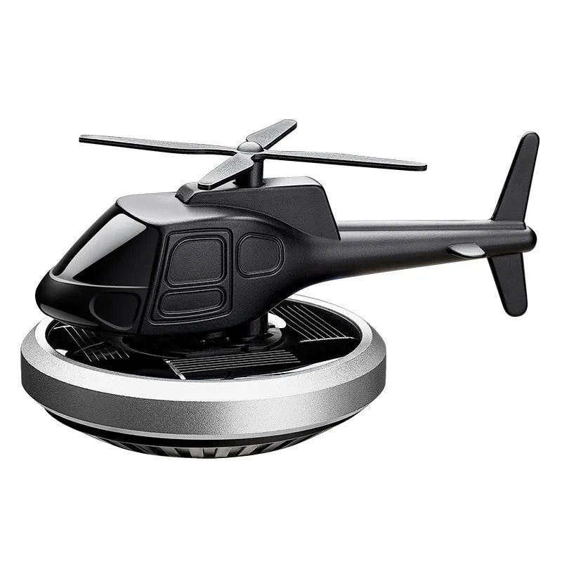 Silver metal solar-powered helicopter car air freshener ornament on a dashboard