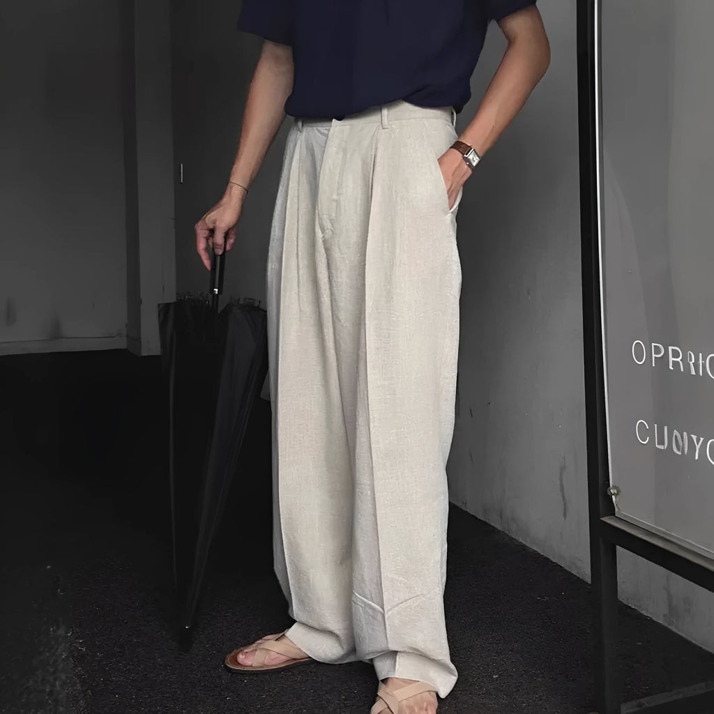 Man wearing loose apricot wide-leg cotton linen blend trousers with a pencil-leg opening.