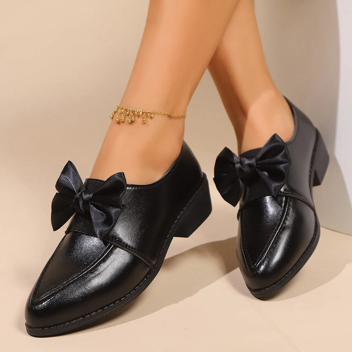 Women's brown leather-look loafers with a large bow detail on the front.