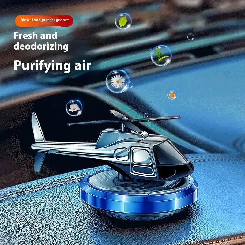 Silver metal solar-powered helicopter car air freshener ornament on a dashboard