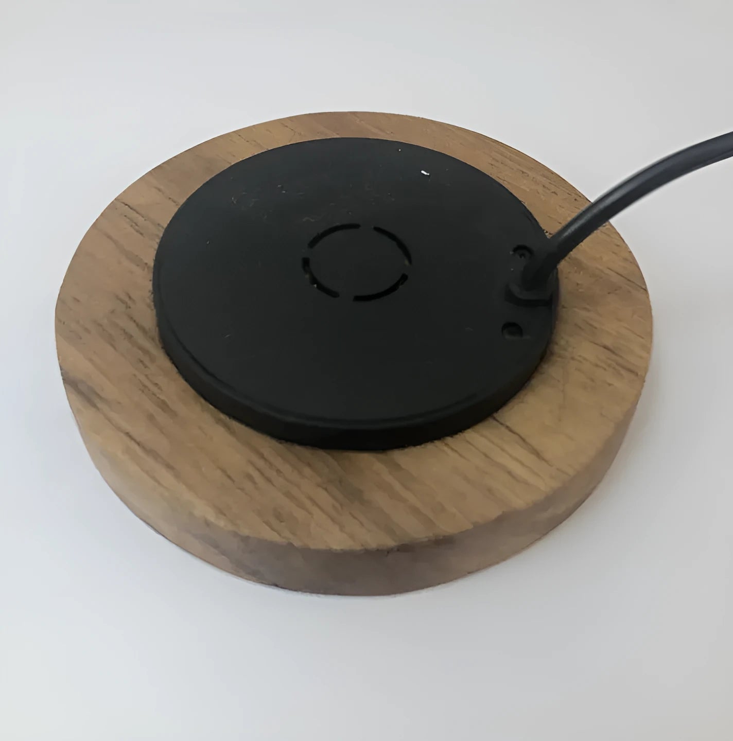 Black round 60mm diameter wireless phone charger for embedding into desk or table surface.