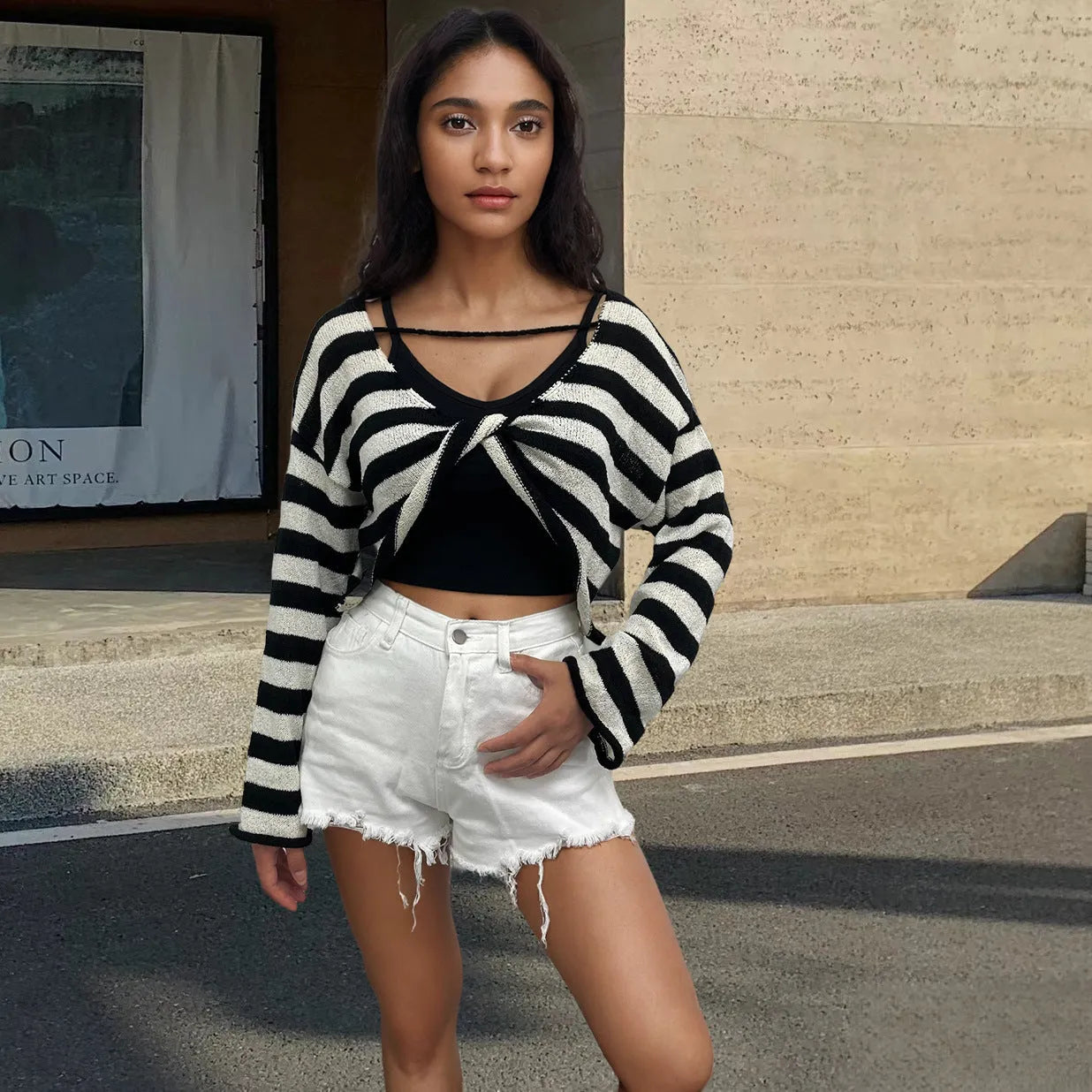 Black and white striped long-sleeved sweater worn as a pullover with an exposed navel style detail.