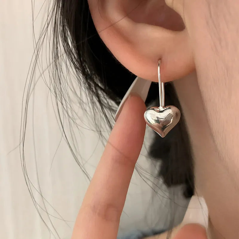 Silver heart-shaped earrings with glossy finish and three-dimensional Korean-style design