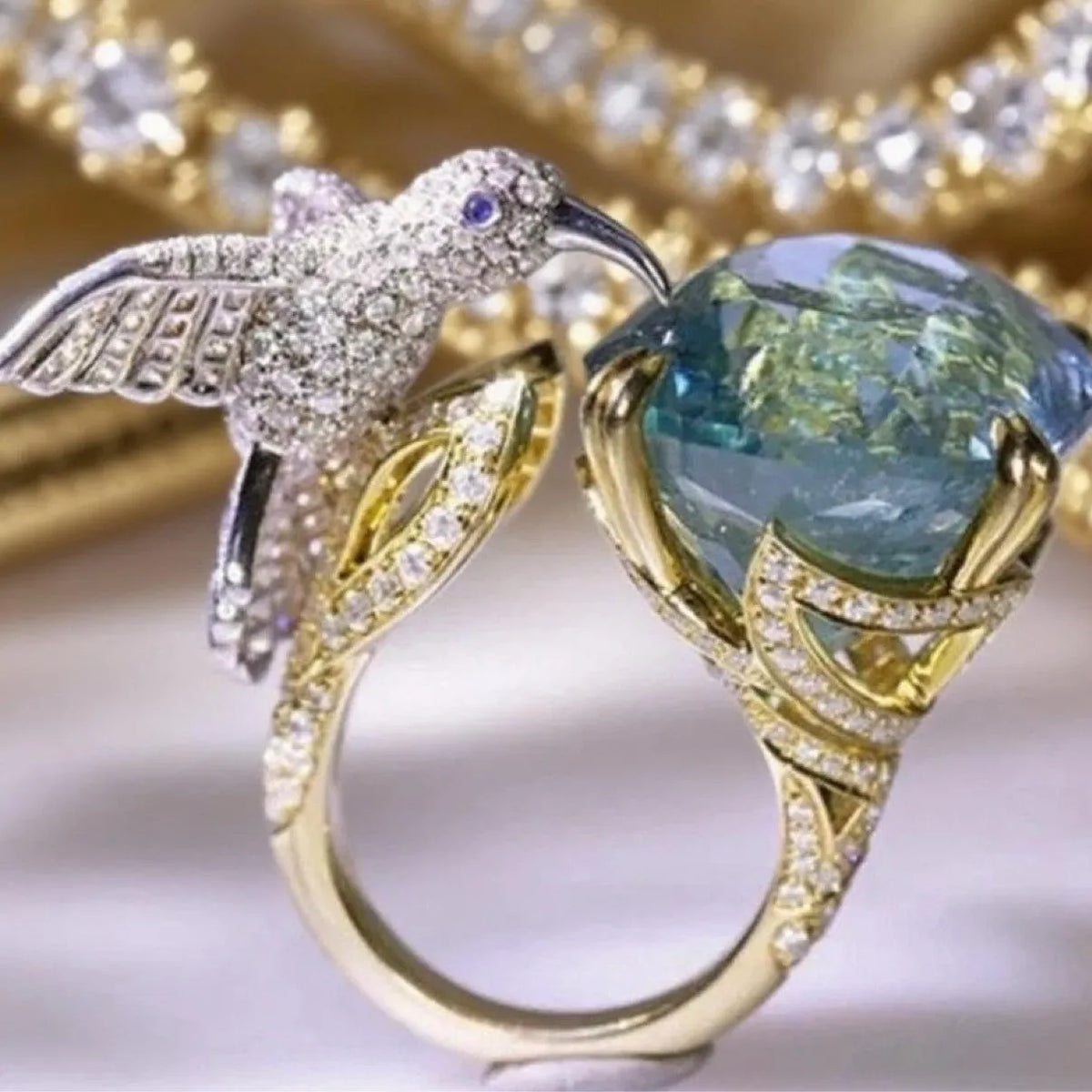 Ocean blue topaz hummingbird open ring with real gold coloured brass finish and adjustable opening.