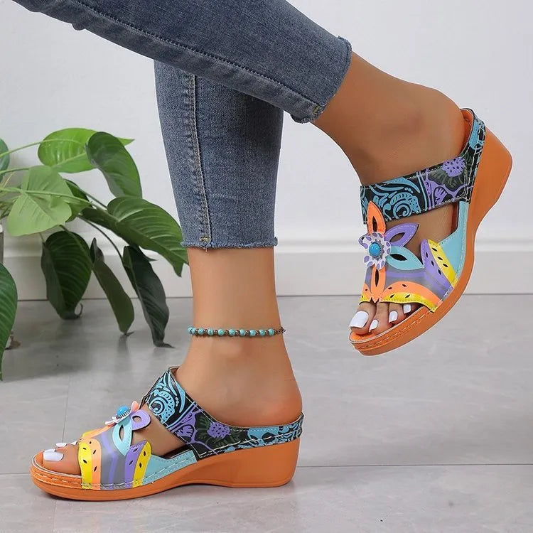 Ethnic patterned cowhide slippers in orange with round toe and rubber sole, shown from the side.