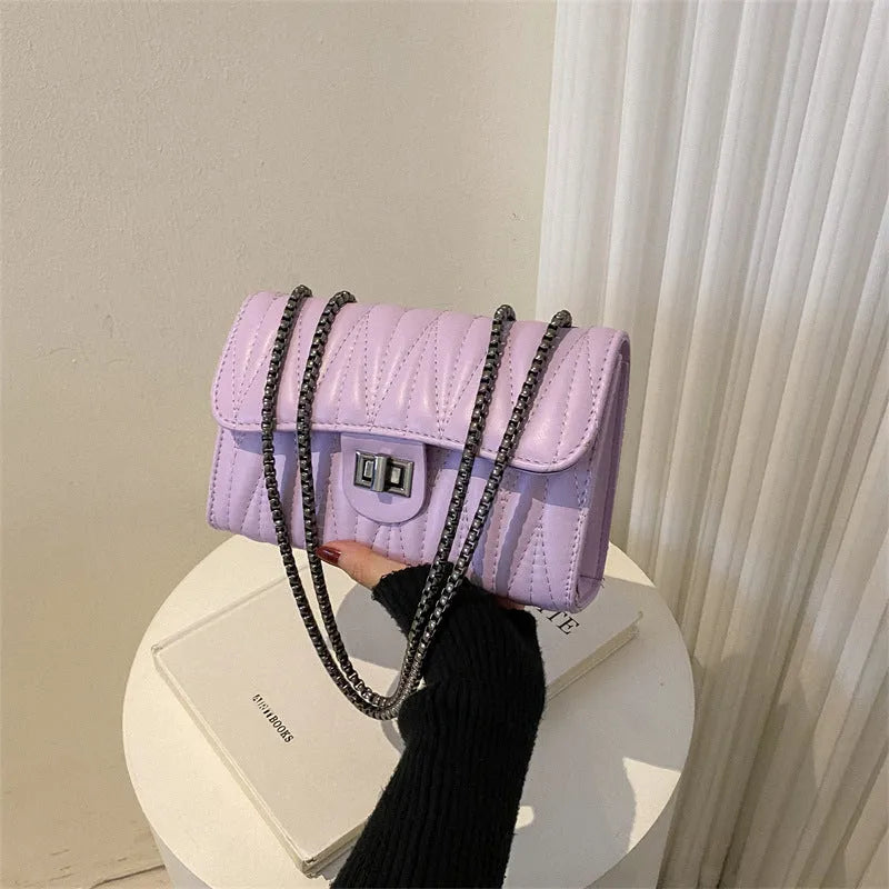 Small beige women's crossbody bag with diamond quilting and a single shoulder strap.
