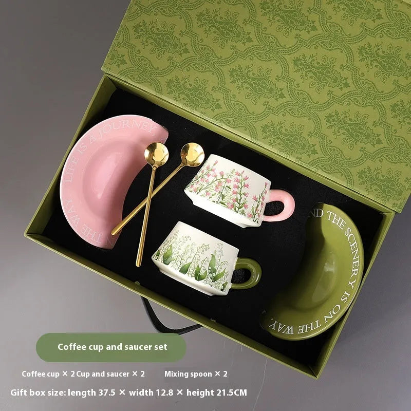 Ceramic coffee cup and saucer set for two people with stirring spoons.