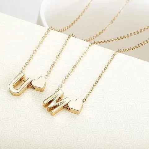 Gold heart shaped alloy pendant with initial letter on white background