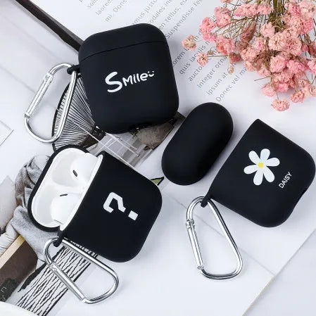 Black AirPods hard case with a smiley face design next to a pink case with a flower pattern.
