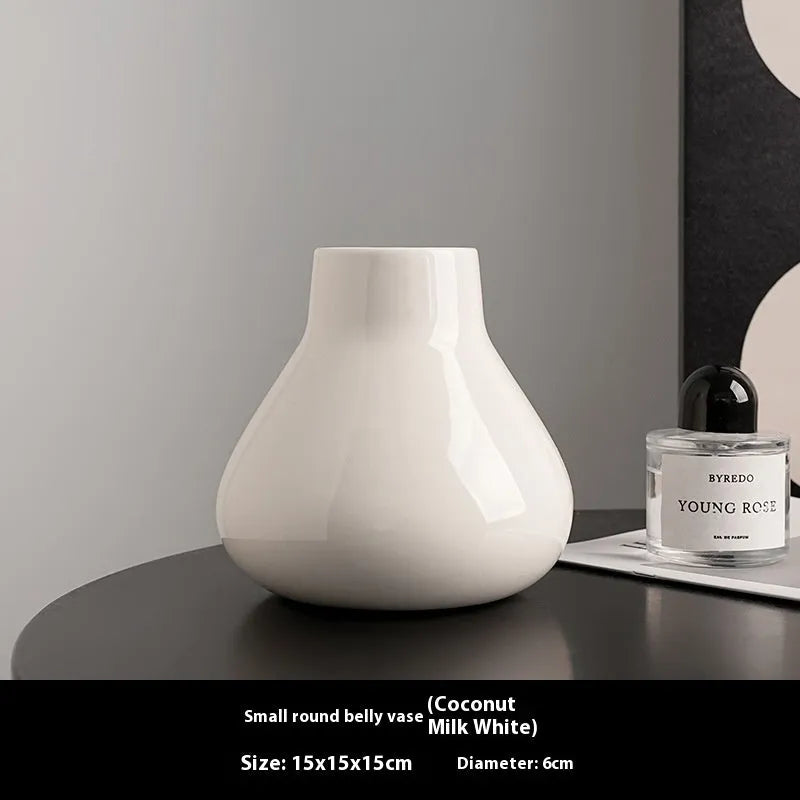 Black ceramic modern vase with white artificial orchid stems on wooden table