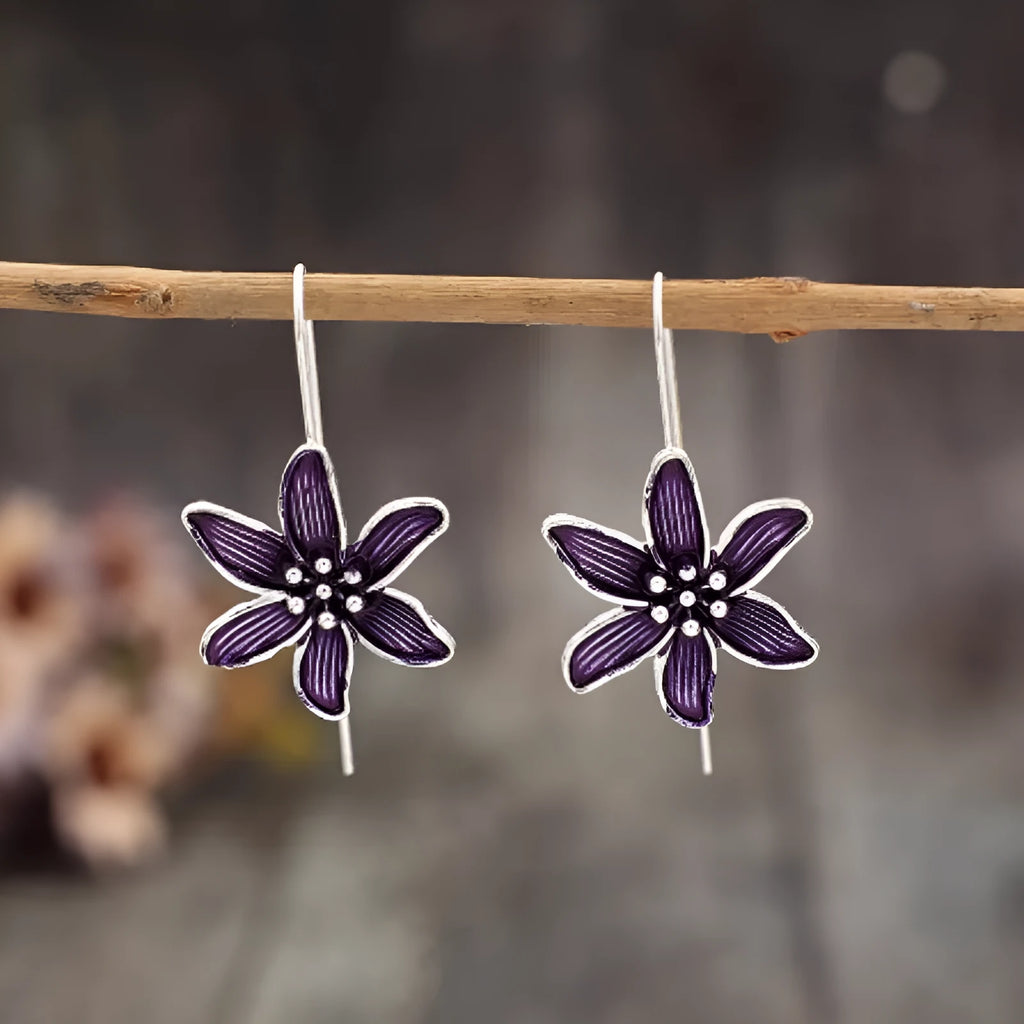 Close-up of a pair of purple flower-shaped alloy stud earrings with an electroplated finish.