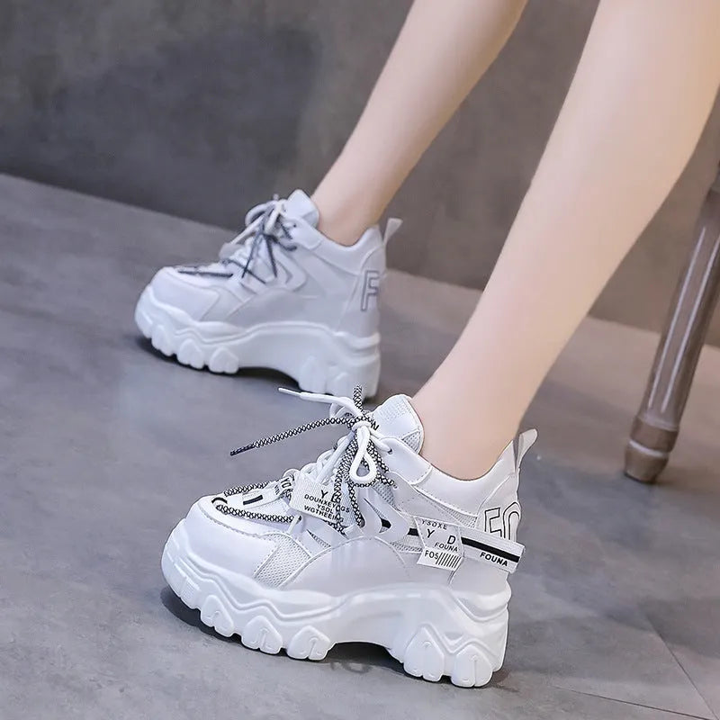 Women's white mesh platform trainers with cross-strap and chunky rubber sole on a neutral background.