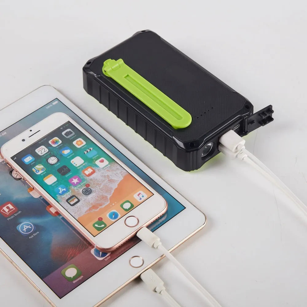 Orange and green hand solar power bank with solar panel, hand crank, dual USB ports, and LED light.