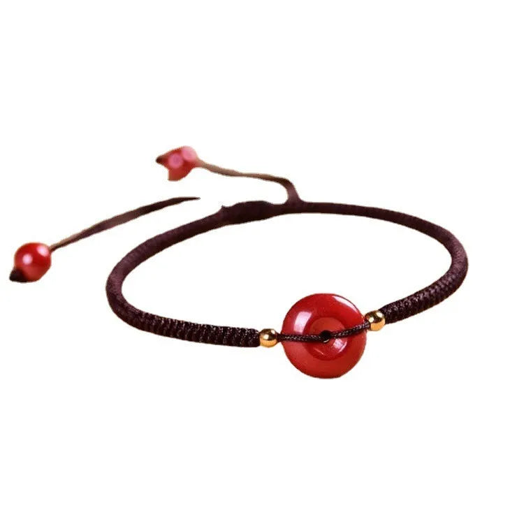 Heart-shaped cinnabar safety buckle bracelet on an adjustable rope cord.