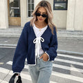 Women's grey lace-up cardigan with crocheted flowers on the front and loose long sleeves.
