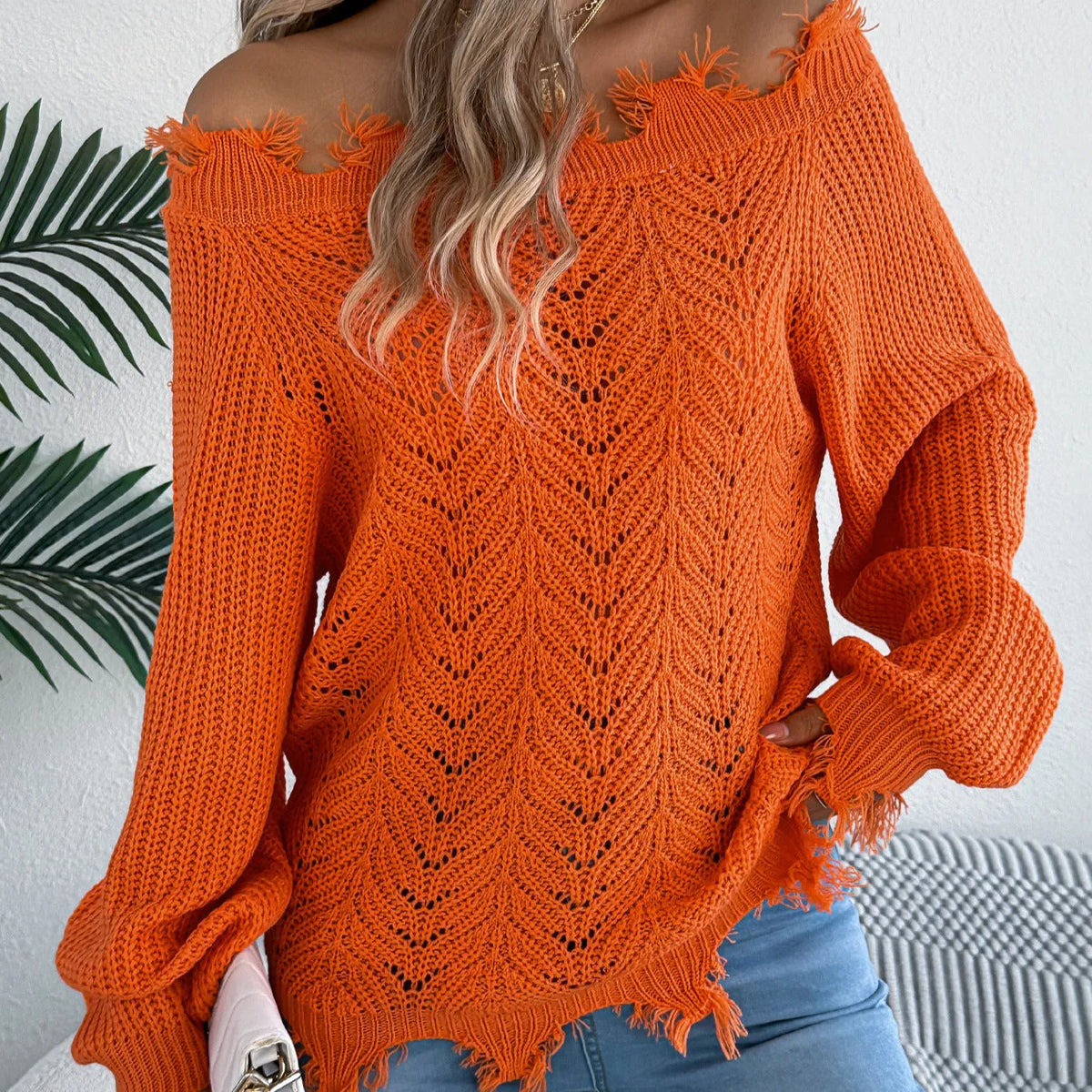 White hollow-out off-the-shoulder long-sleeve pullover sweater laid flat.