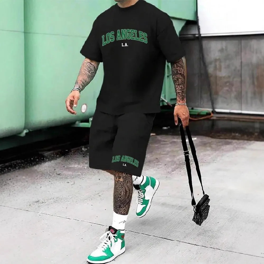 Man wearing a grey 3D printed letter short sleeve top and matching shorts from a sports co-ord set.