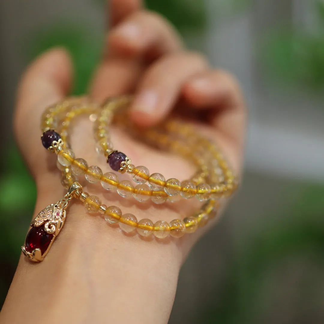 Natural Brazil gold rutilated quartz Chinese style bracelet with three gold rings and chopstick hanging detail.