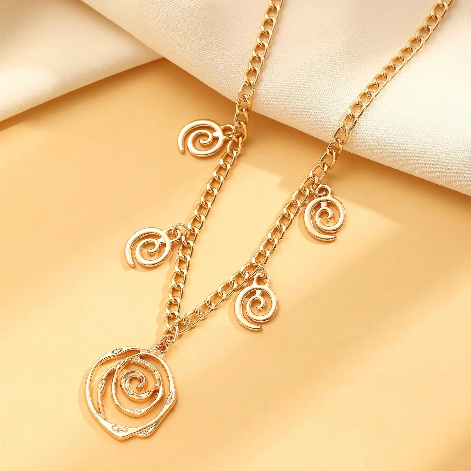 Spiral donut jewellery set showing necklace, bracelet, and earrings in geometric circle design with gold electroplated finish