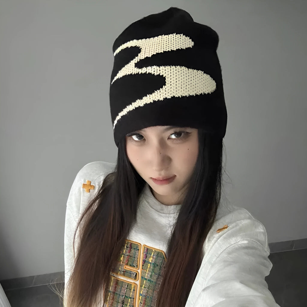 Acrylic knit beanie hat in black on a grey background, showing ribbed texture.