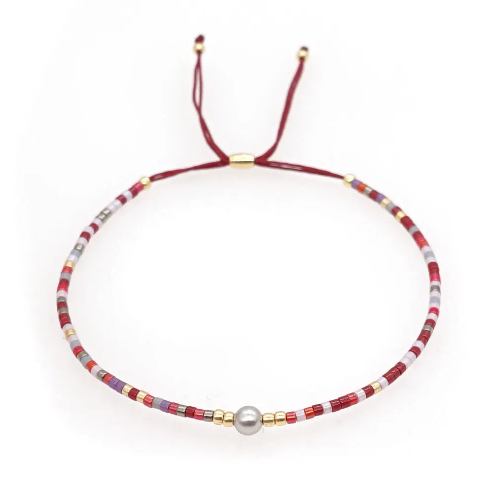 Handmade colourful beaded bracelet with semi-precious stone and glass charms on a wrist.