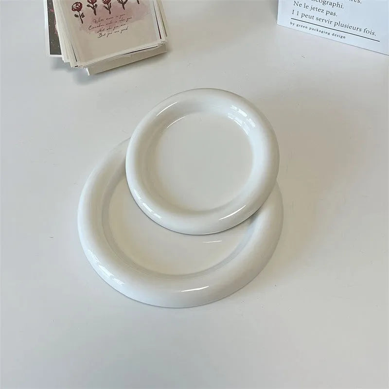 White porcelain plant saucer with a bear doodle design, shown next to a potted plant.
