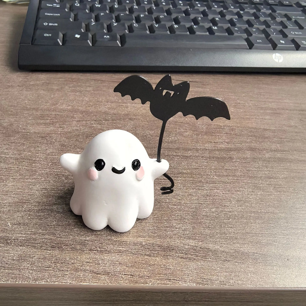 Miniature resin ghost figurine holding a bat, a compact Halloween decoration ornament.