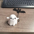 Miniature resin ghost figurine holding a bat, a compact Halloween decoration ornament.
