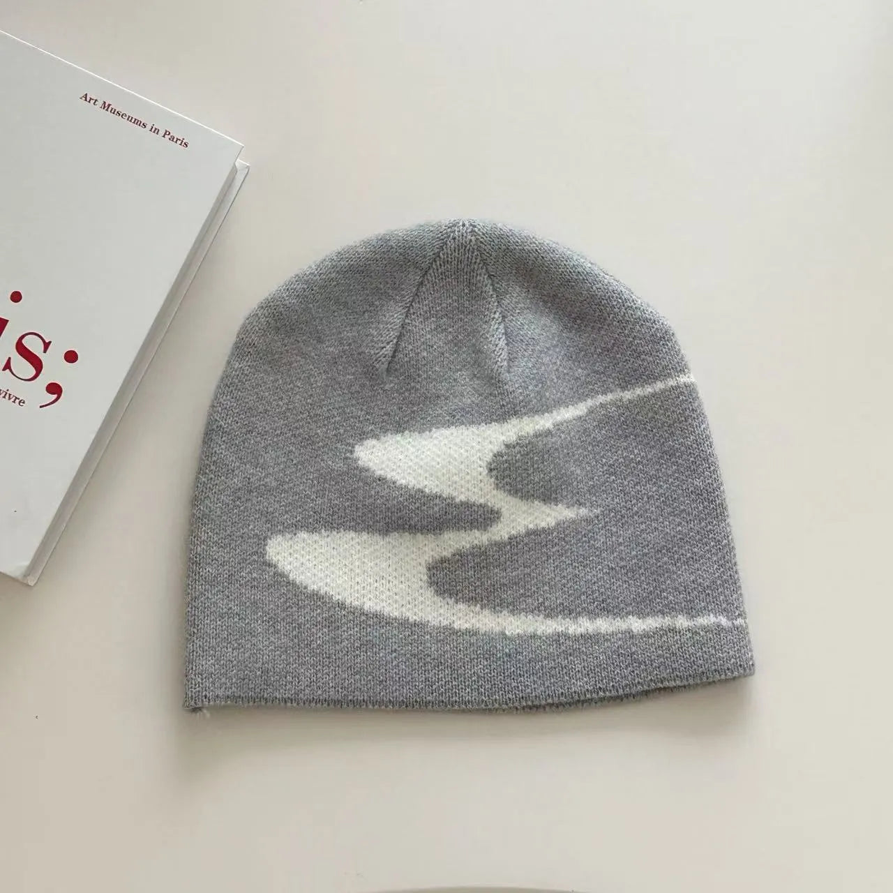 Acrylic knit beanie hat in black on a grey background, showing ribbed texture.