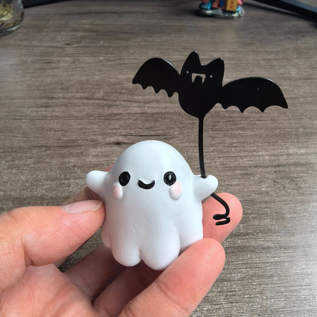 Miniature resin ghost figurine holding a bat, a compact Halloween decoration ornament.