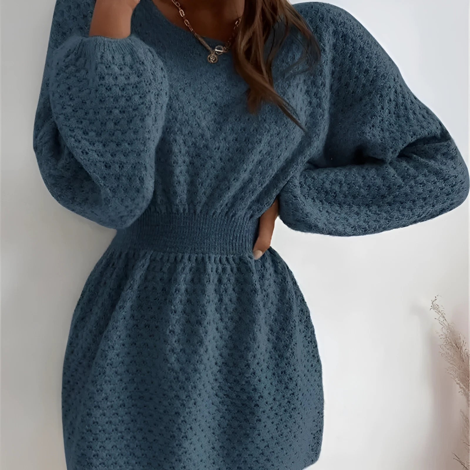Blue women's knitted dress with hand-crocheted flowers, fitted waist, and round neck.