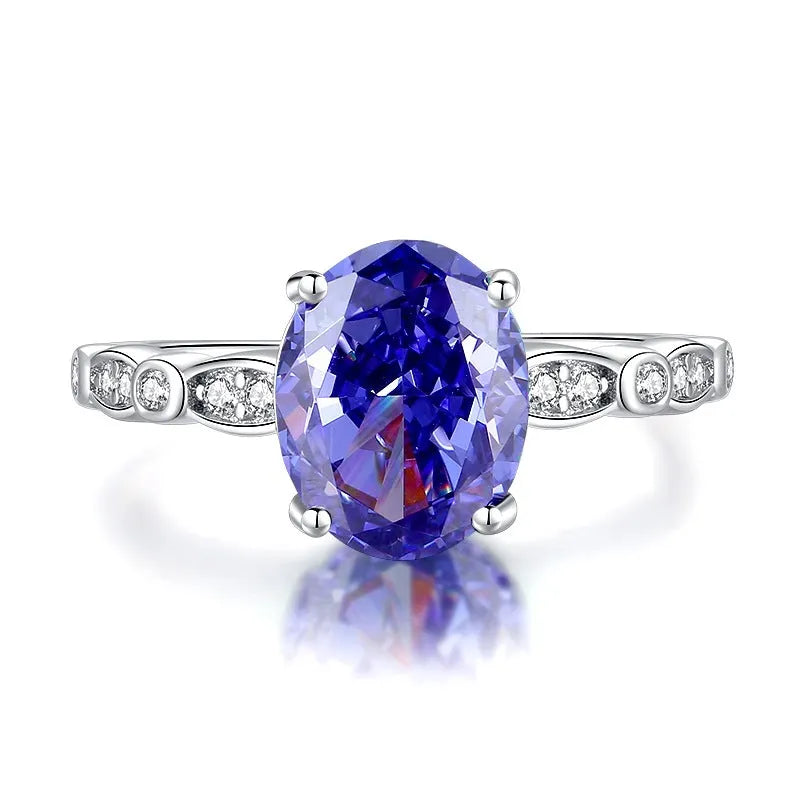 Close-up of a sterling silver heart-shaped ring with a floral-cut blue zircon stone.