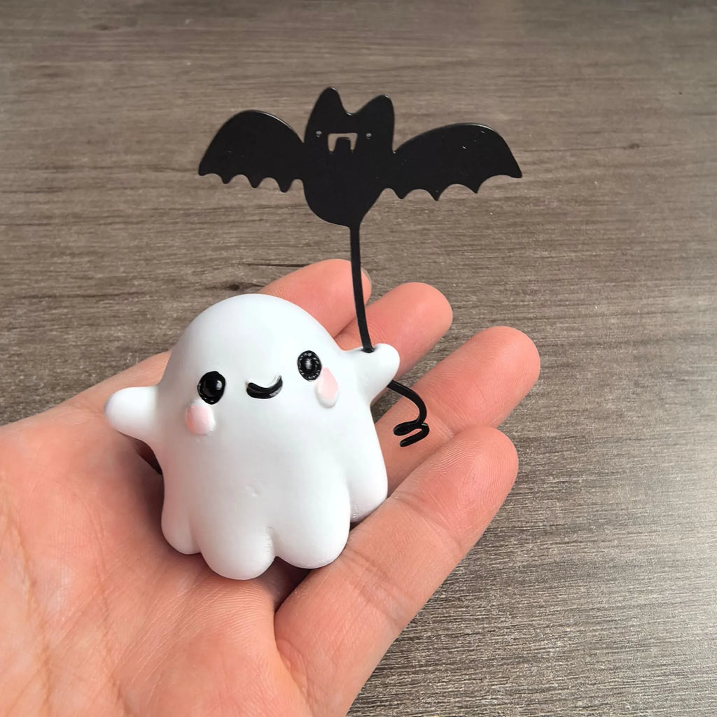 Miniature resin ghost figurine holding a bat, a compact Halloween decoration ornament.