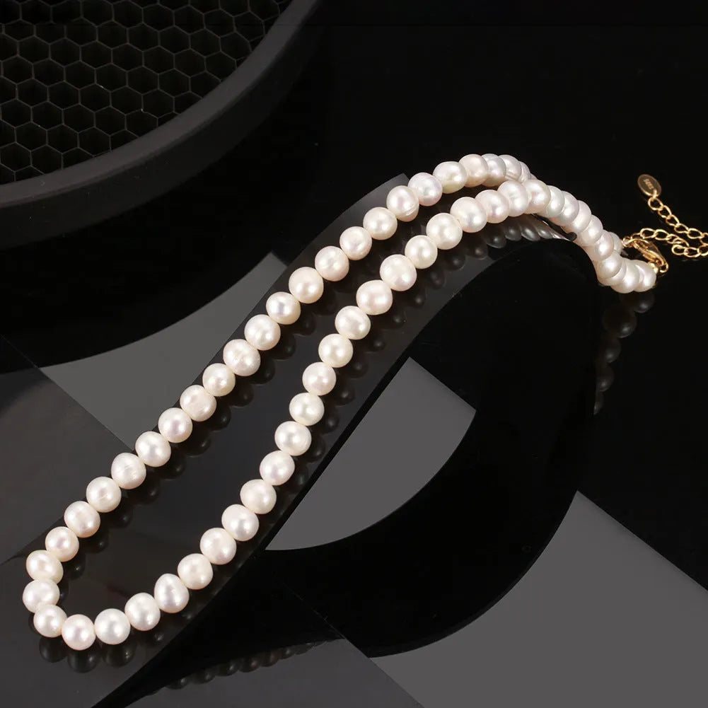 Women's simple sterling silver necklace with round freshwater pearls on an adjustable chain.