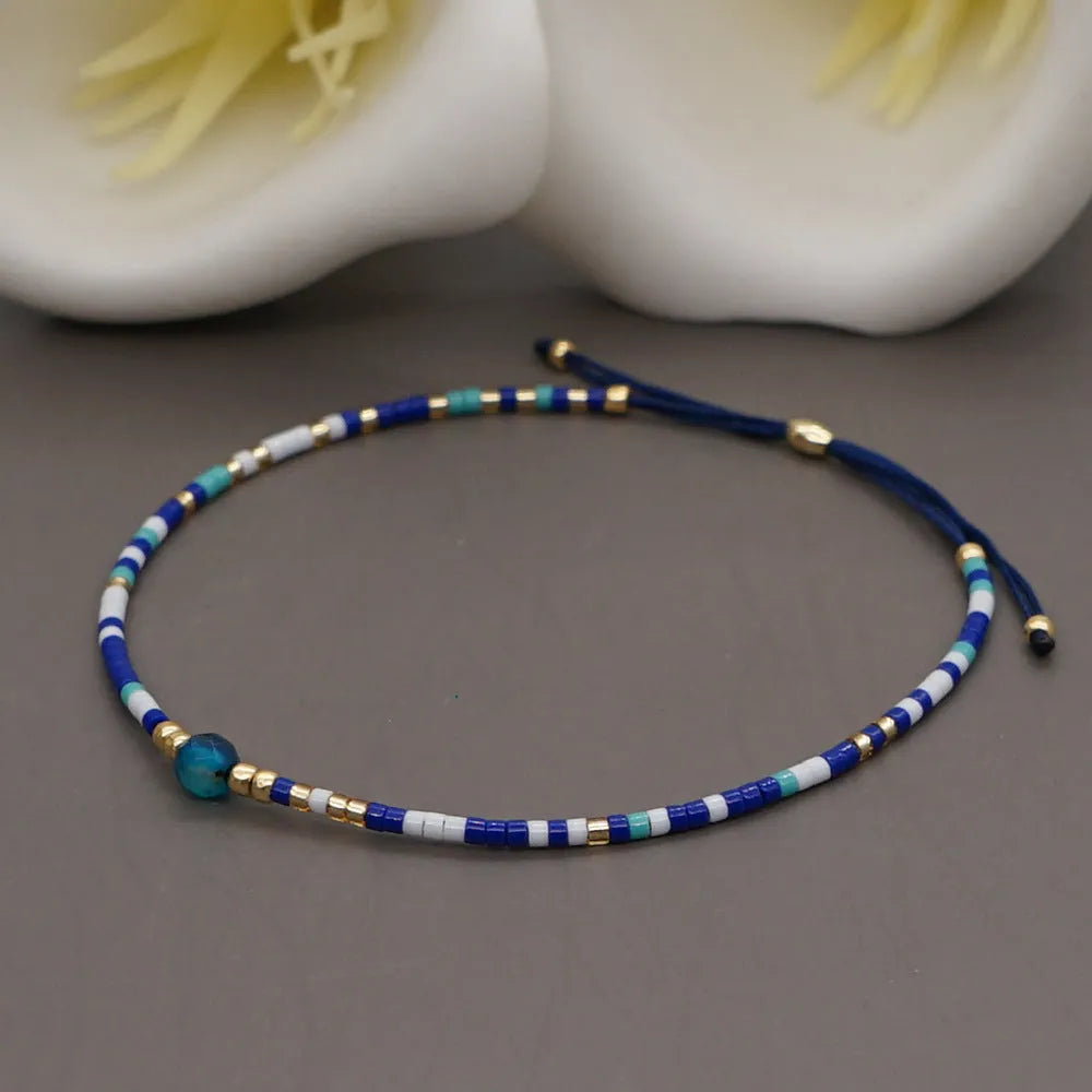 Handmade colourful beaded bracelet with semi-precious stone and glass charms on a wrist.