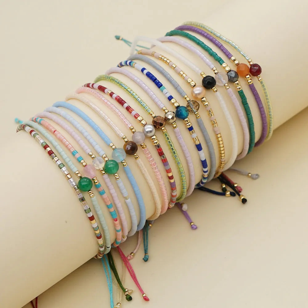 Handmade colourful beaded bracelet with semi-precious stone and glass charms on a wrist.