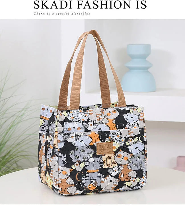 Women's printed canvas handbag showing floral or cat design on black, blue or pink background