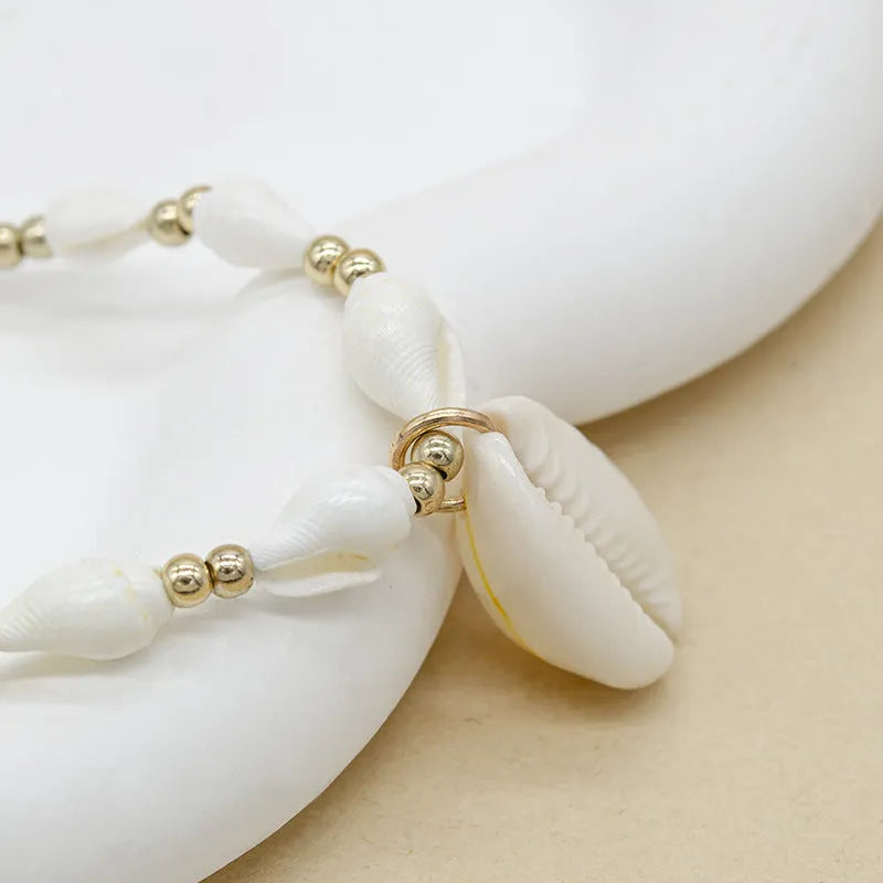 White necklace with a natural shell-shaped mother of pearl pendant on a metal chain.