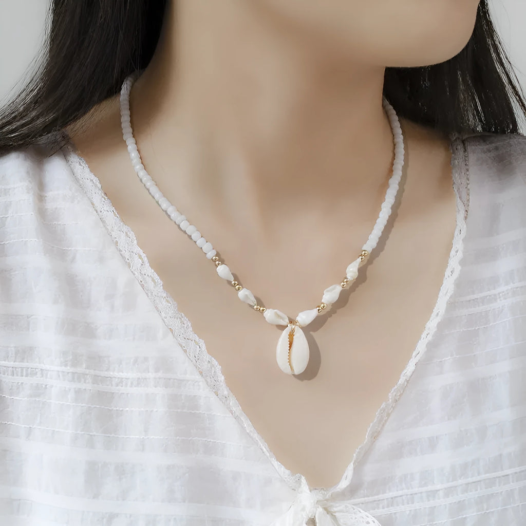 White necklace with a natural shell-shaped mother of pearl pendant on a metal chain.