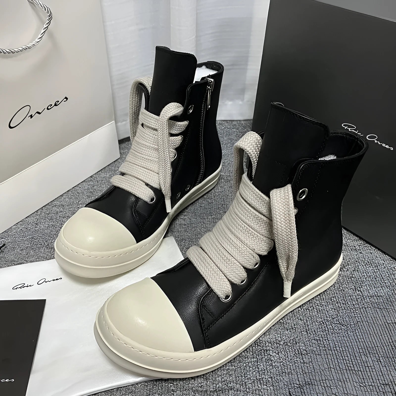 Black high-top leather sneakers with side zipper and round toe on a white background