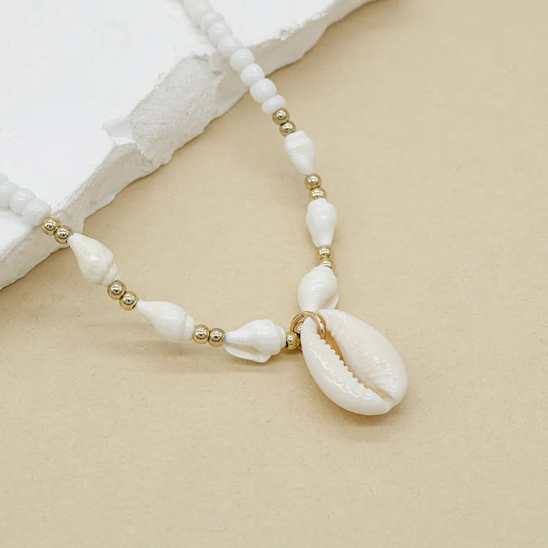 White necklace with a natural shell-shaped mother of pearl pendant on a metal chain.