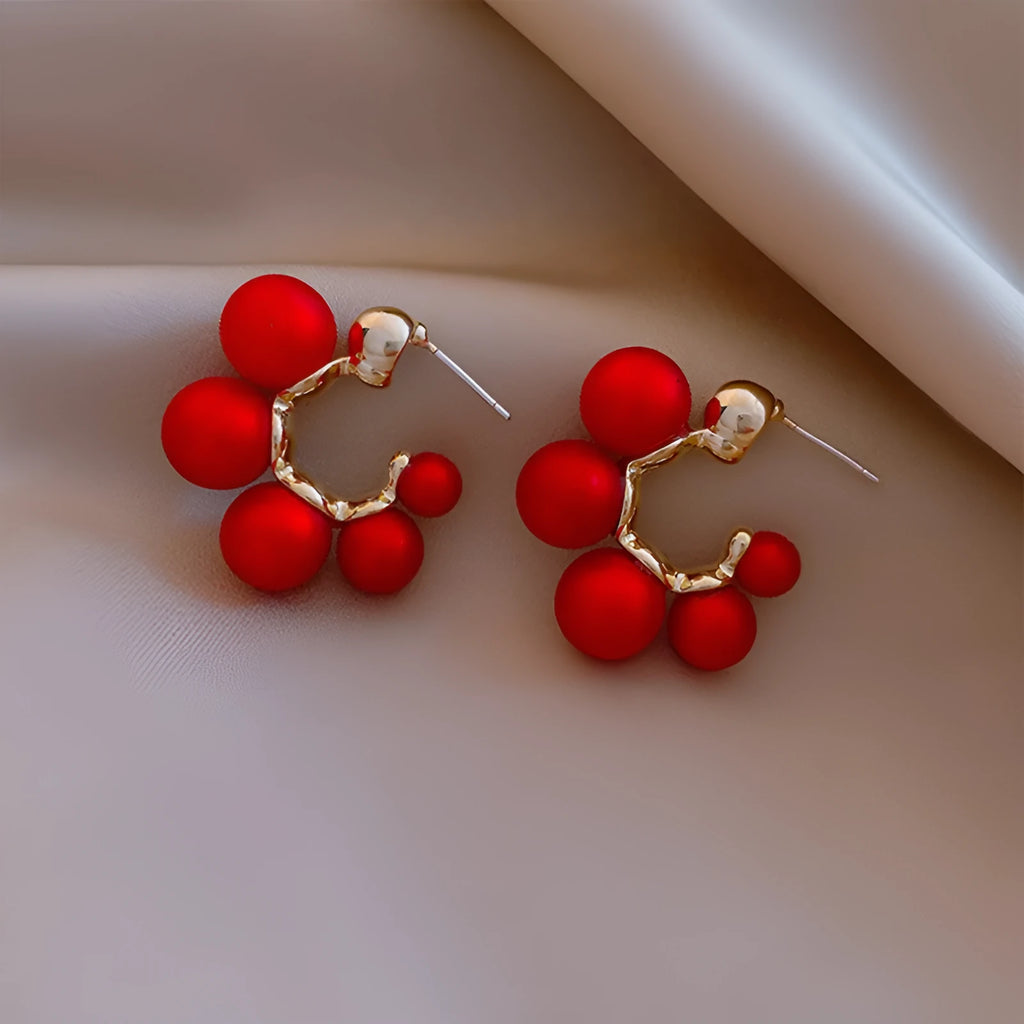 A pair of red bell charm earrings made from alloy metal with a silver tone finish.