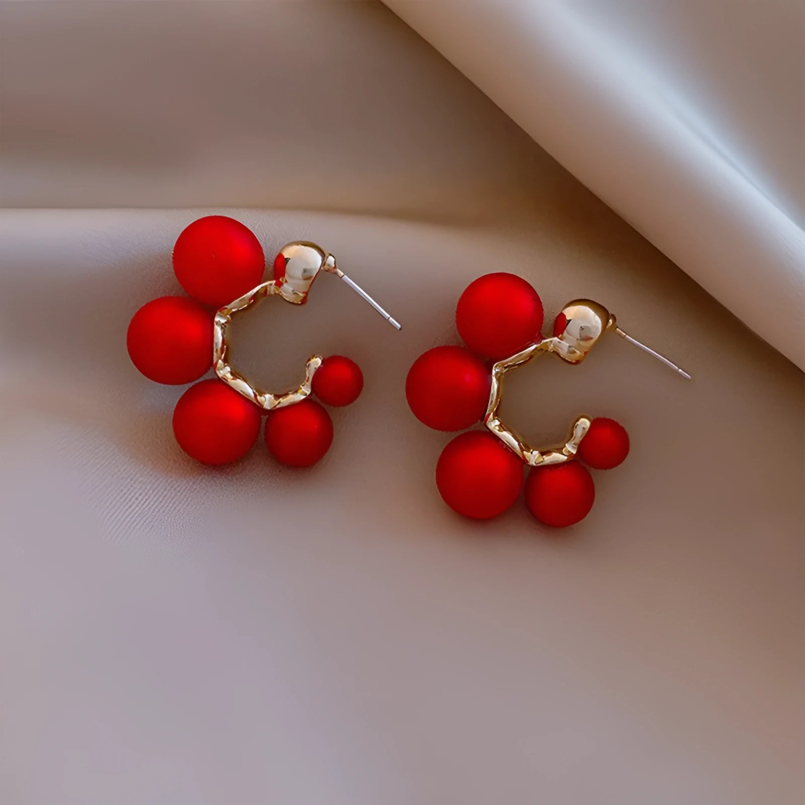 A pair of red bell charm earrings made from alloy metal with a silver tone finish.