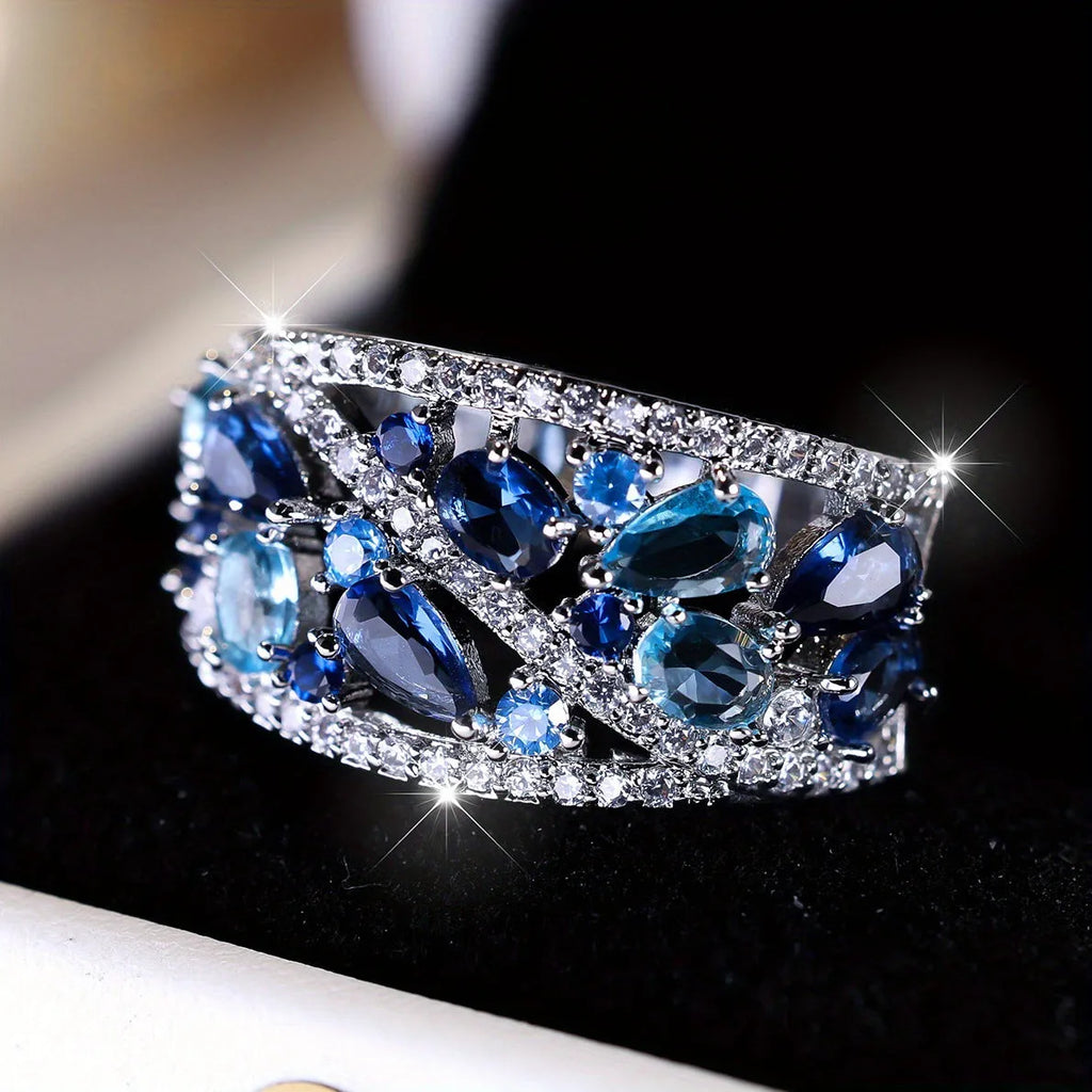 Women's hollow round fashion ring in gold or platinum finish with sapphire blue or white diamond accents