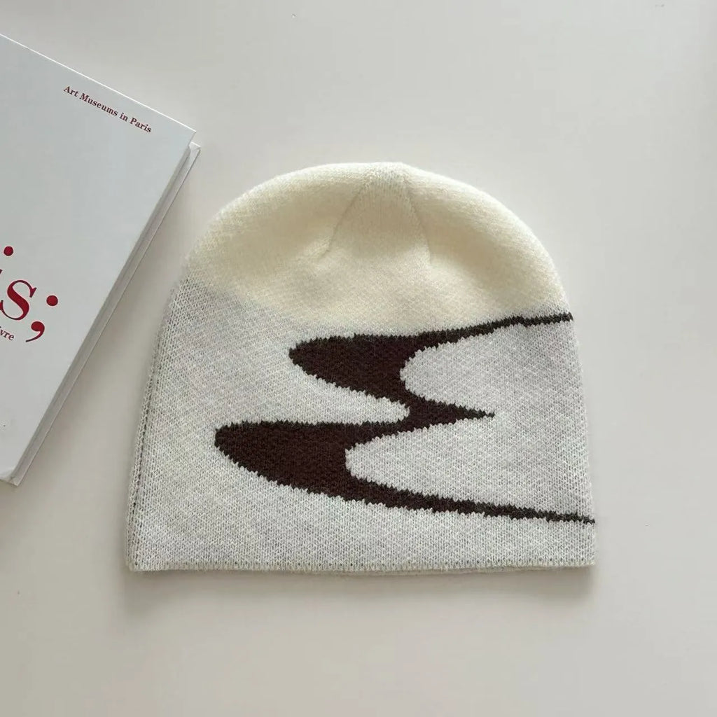 Acrylic knit beanie hat in black on a grey background, showing ribbed texture.