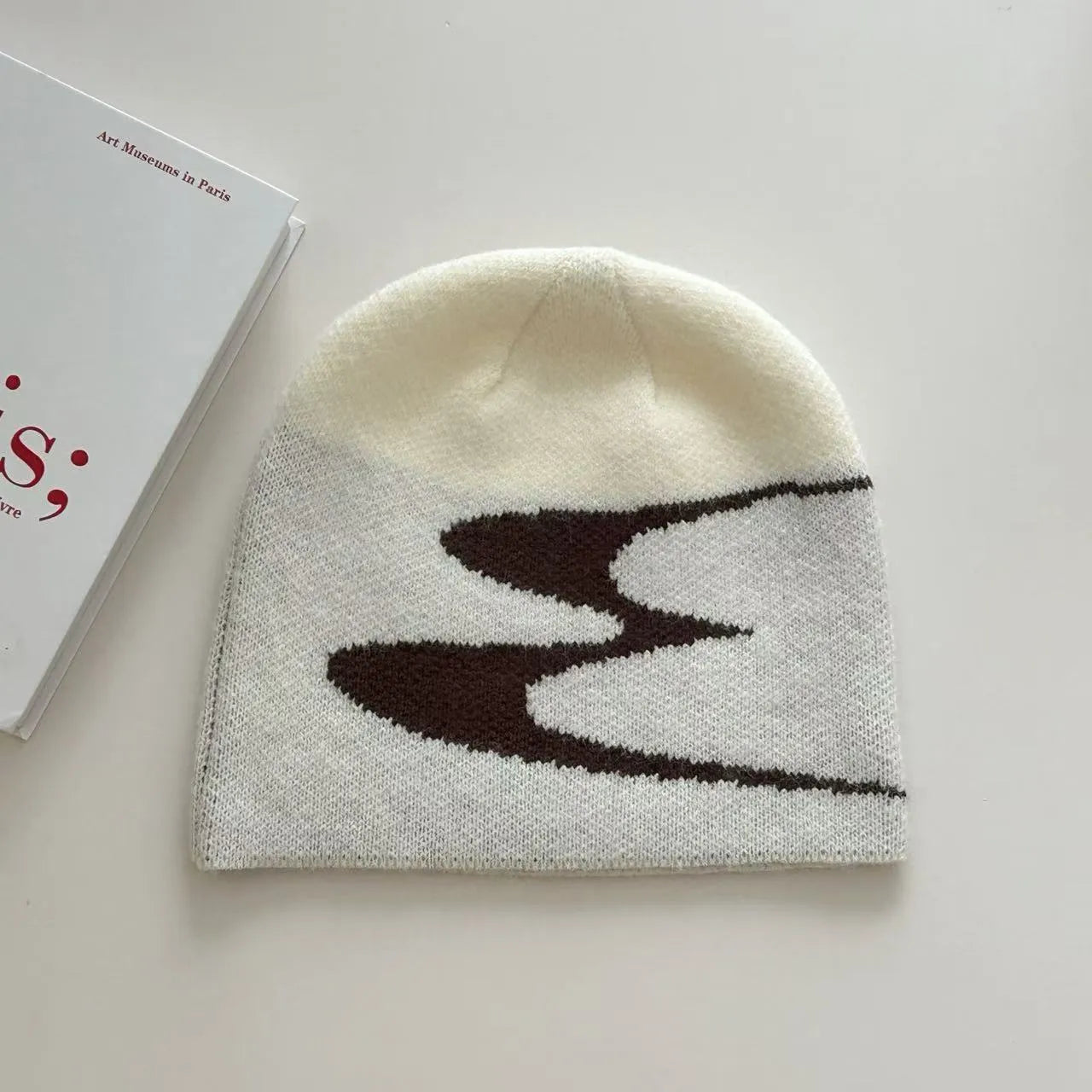 Acrylic knit beanie hat in black on a grey background, showing ribbed texture.