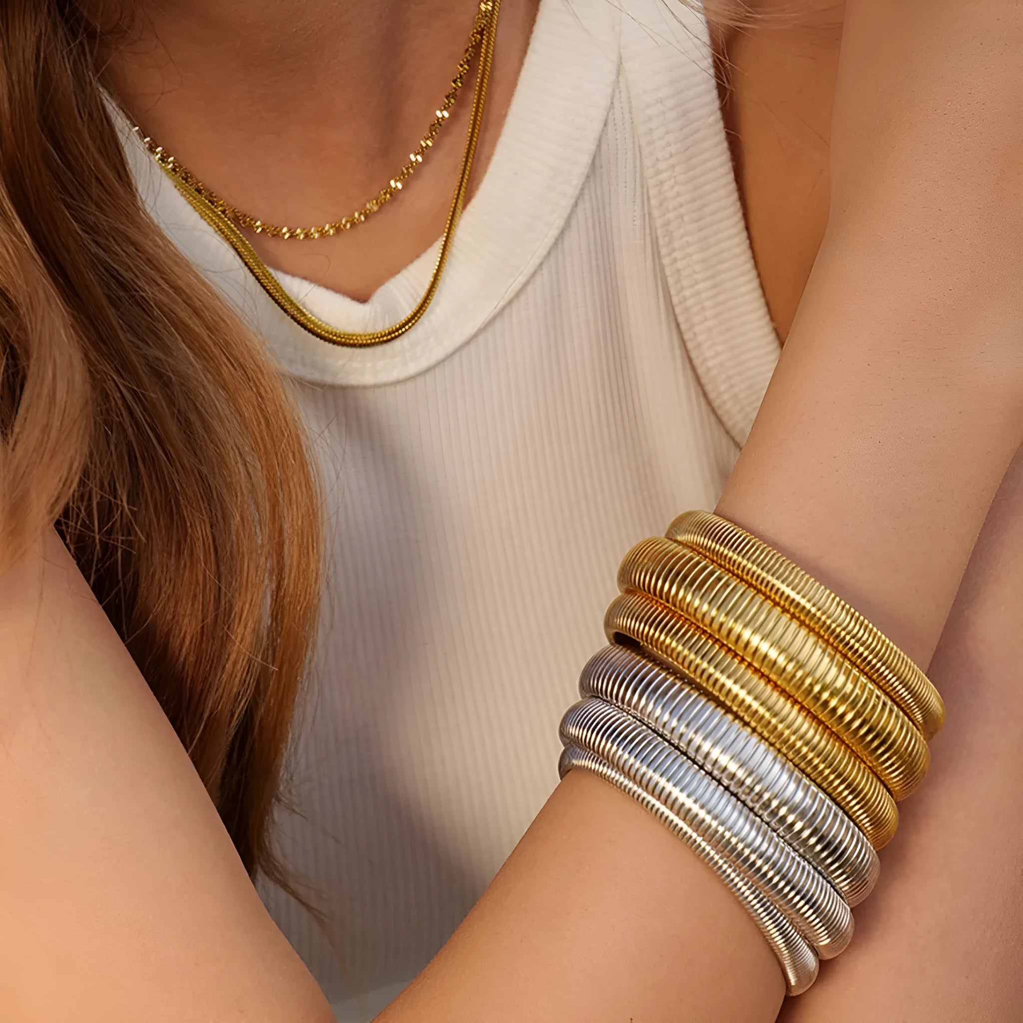Close-up of a women's titanium steel bracelet with an exaggerated vertical stripe ring elastic design in a gold finish.